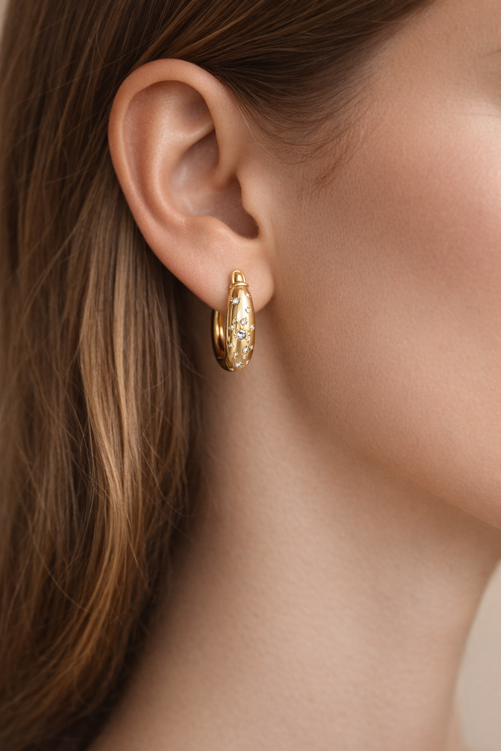 Pendientes Huggie de Estrella con Circonitas Baño Oro 18 Kilates puestos en la oreja, detalle de cerca
